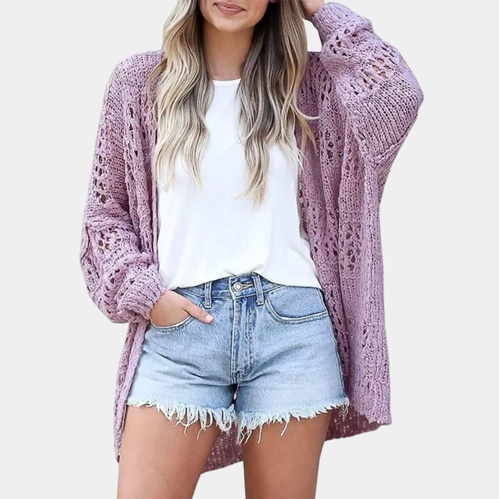 Vrouw draagt paarse gehaakte cardigan, witte top en denim shorts. Modieuze dameskleding, casual zomeroutfit, trendy stijl.