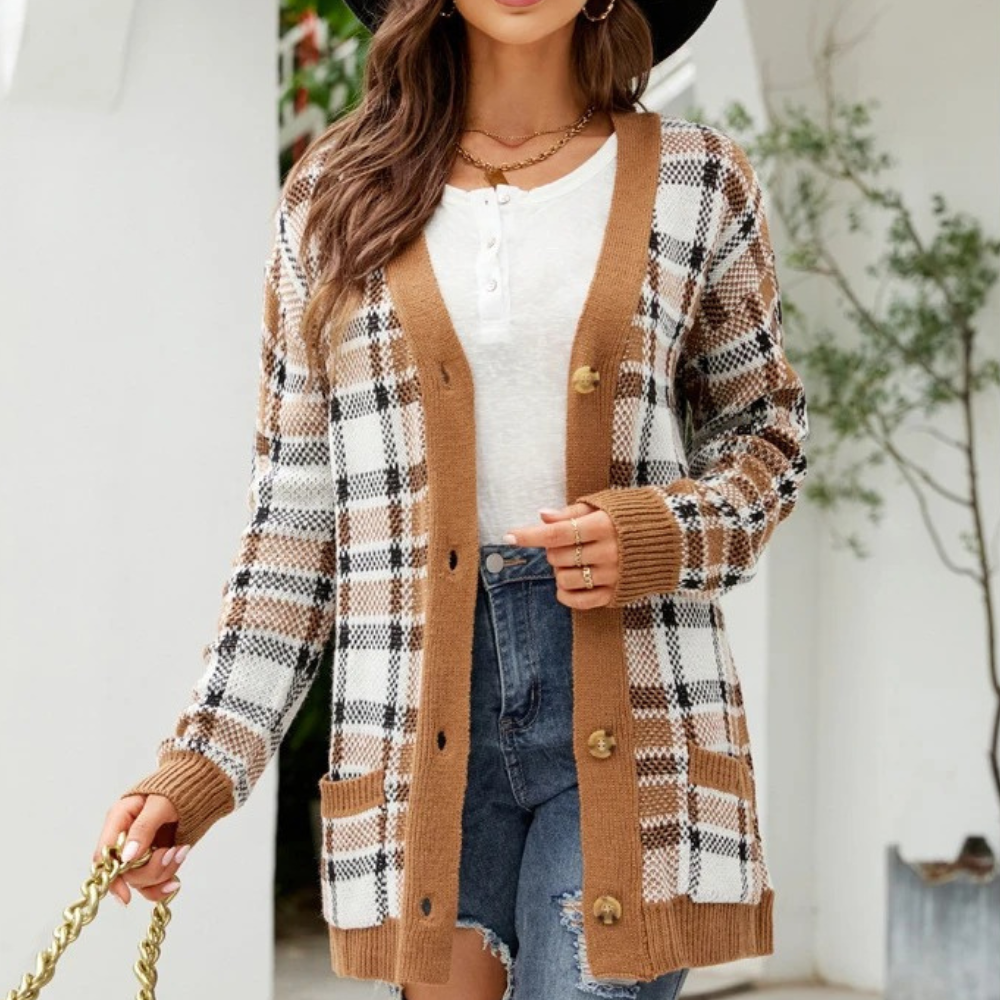 Vrouw in geruite bruine en witte cardigan, witte top, jeansshort en zwarte hoed. Modieuze herfstoutfit, casual dameskleding, trendy stijl.