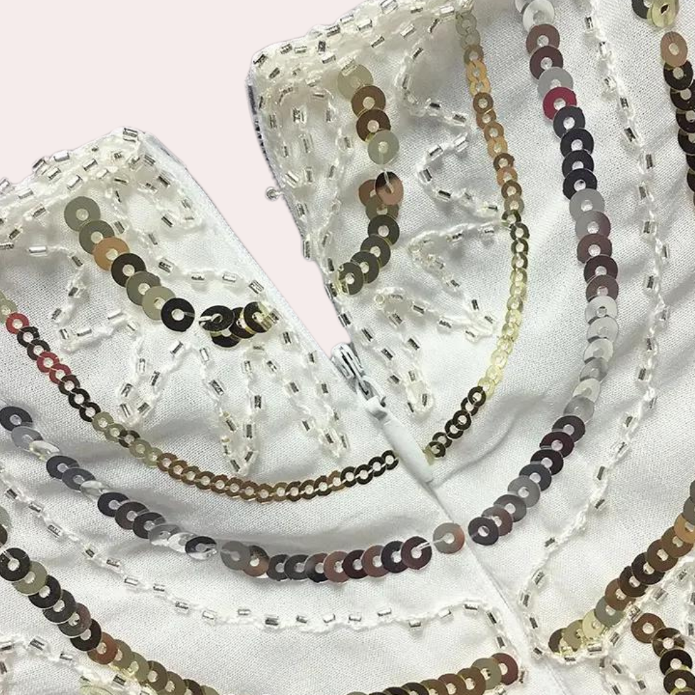 Witte stof met glanzende pailletten en kralen, decoratief patroon. Ideaal voor modeontwerp, bruidskleding, feestelijke kleding.