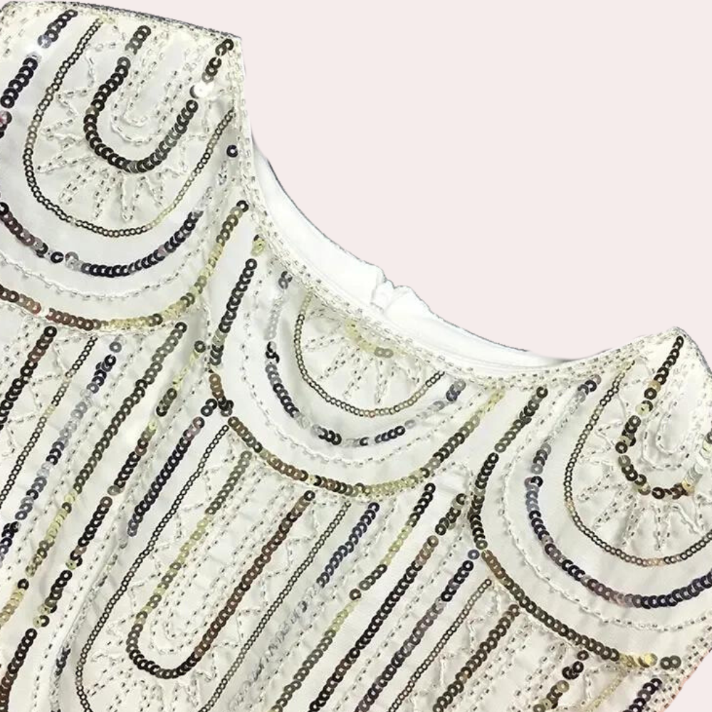Witte jurk met pailletten, art-deco patroon, elegante avondkleding, feestelijke mode, verfijnde stijl, glinsterende details, dameskleding.