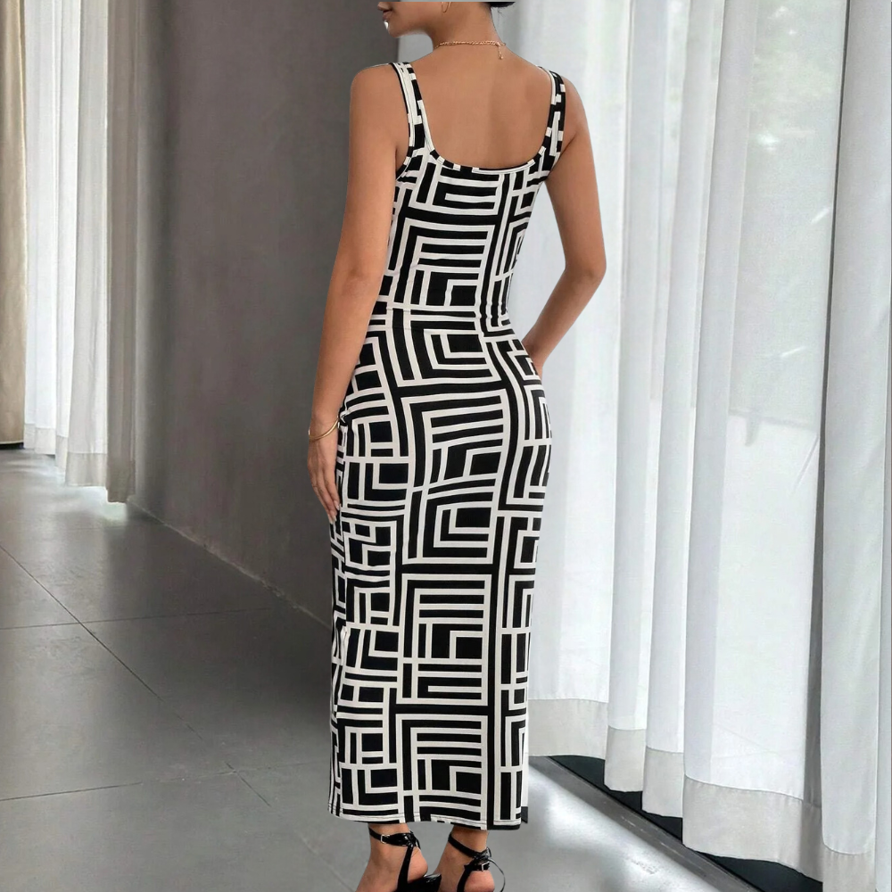 Zwarte jurk met geometrisch patroon, mouwloos en knielang, gedragen door model in moderne interieursetting. Perfect voor avondkleding en mode-inspiratie.