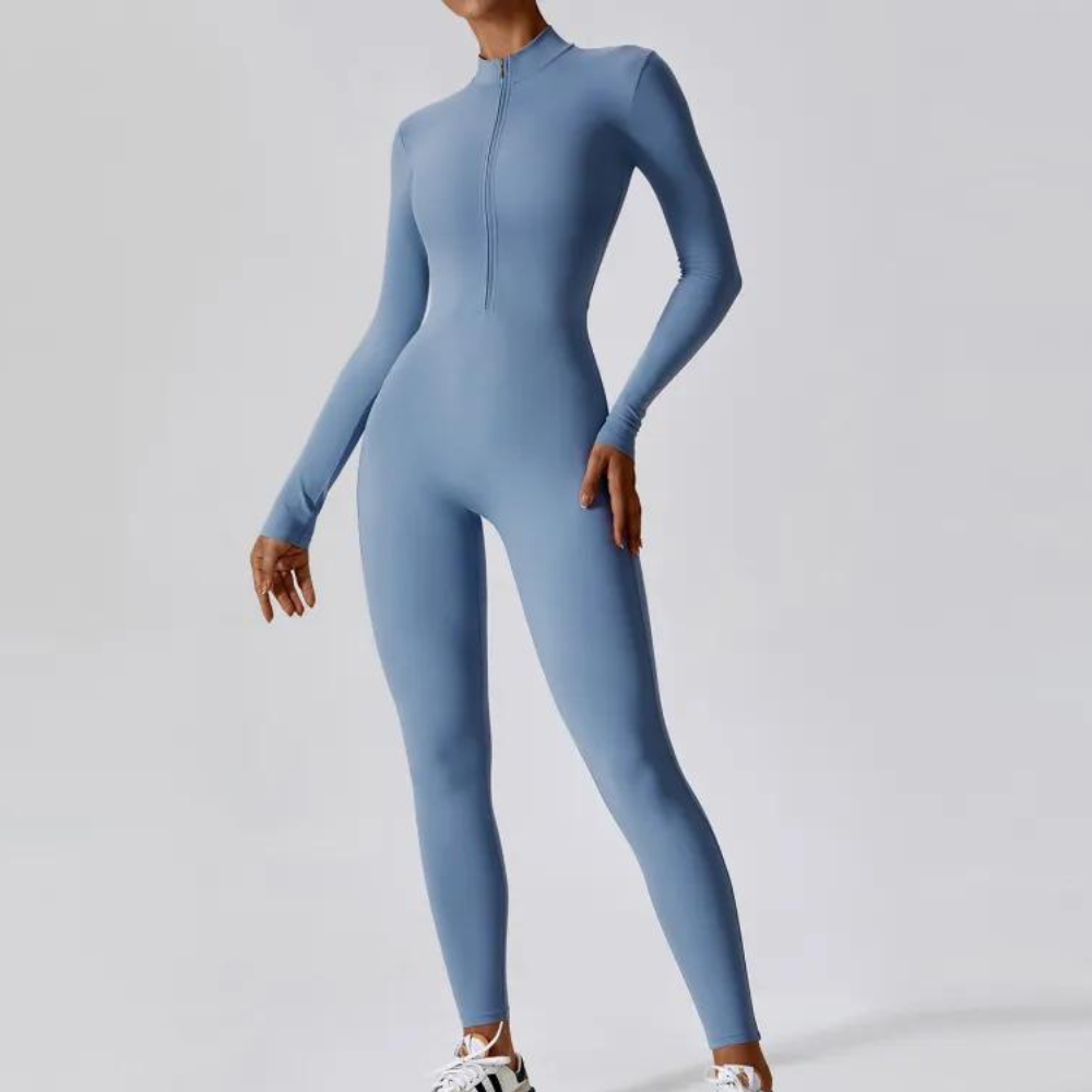 Vrouw in lichtblauwe sportieve jumpsuit, lange mouwen, ritssluiting, strakke pasvorm, geschikt voor yoga of fitness, modieuze sportkleding.