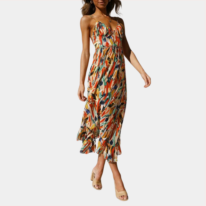 Vrouw in kleurrijke zomerjurk met abstract patroon, spaghetti bandjes en ruches, perfect voor casual en strandoutfits. Trendy damesmode.