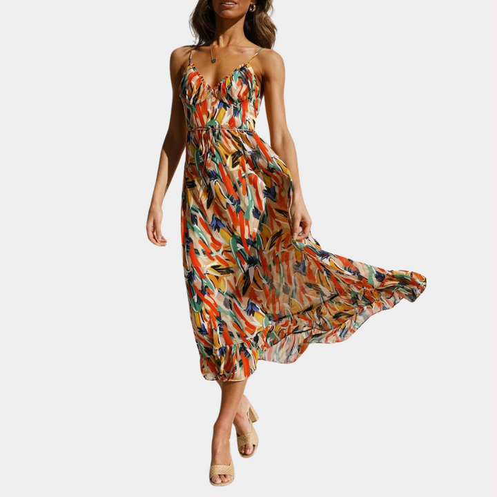 Vrouw in kleurrijke zomerjurk met abstract patroon, spaghetti bandjes en vloeiende rok. Perfect voor zomermode en strandkleding.