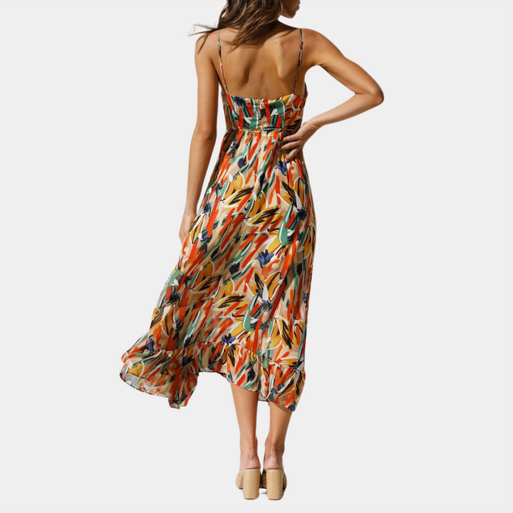 Vrouw in kleurrijke zomerjurk met abstract patroon, spaghetti bandjes en zwierige rok. Perfect voor casual en strandmode.