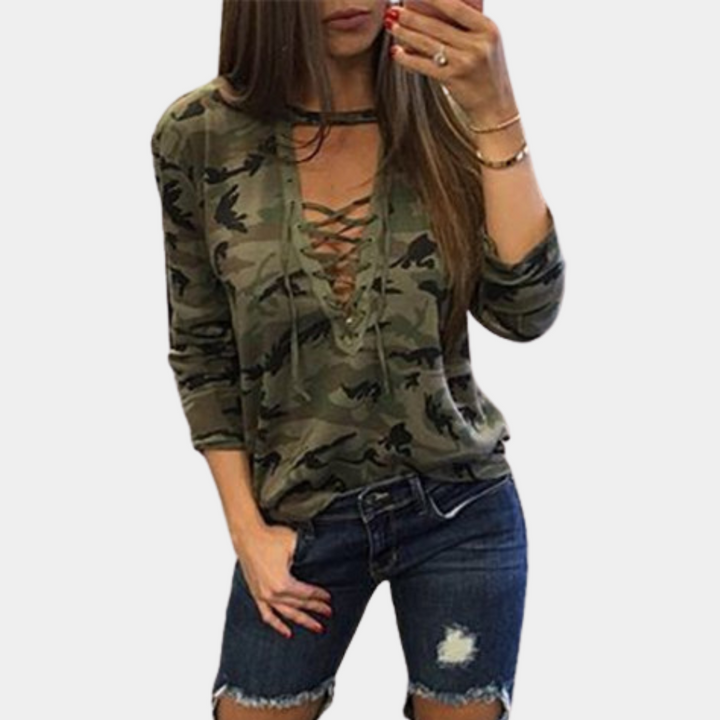 Vrouw in legergroene camouflage top met vetersluiting, gecombineerd met gescheurde denim shorts. Modieuze casual dameskleding.