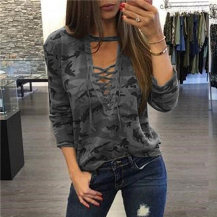 Grijze camouflage damestrui met veterhals, casual mode, lange mouwen, gedragen door vrouw in winkel. Trendy kleding, comfortabele pasvorm.