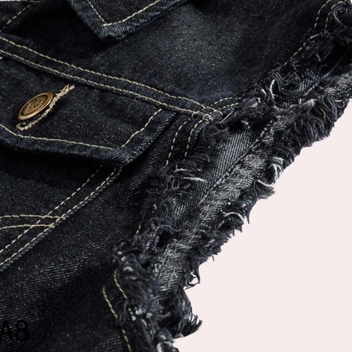 Versleten zwarte denim short met rafelige zoom en koperen knoop. Trendy spijkerstof, casual mode, streetwear stijl. Perfect voor zomerse outfits.