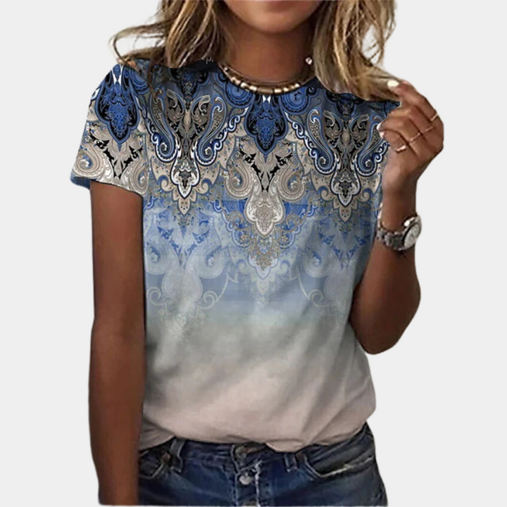 Vrouw draagt blauw-wit T-shirt met paisley patroon, casual stijl, korte mouwen. Perfect voor zomermode, trendy dameskleding.
