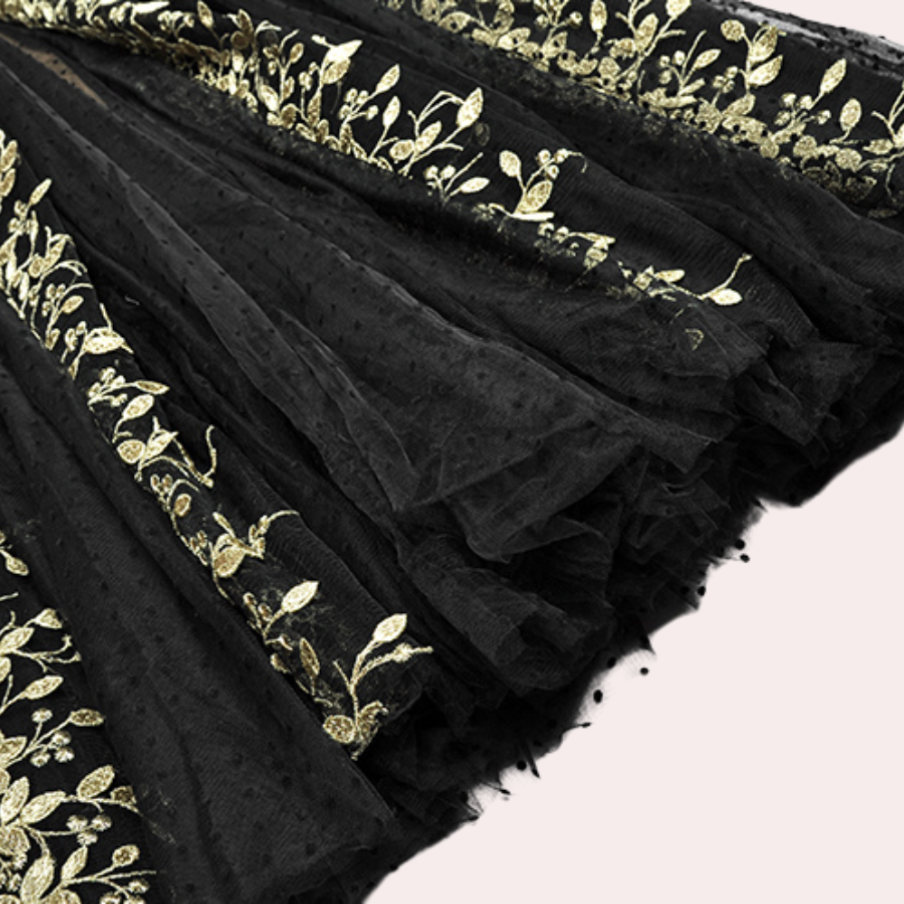 Zwarte tule stof met gouden bladmotief, geschikt voor avondjurken en luxe kleding. Elegante en verfijnde textielkeuze voor speciale gelegenheden.