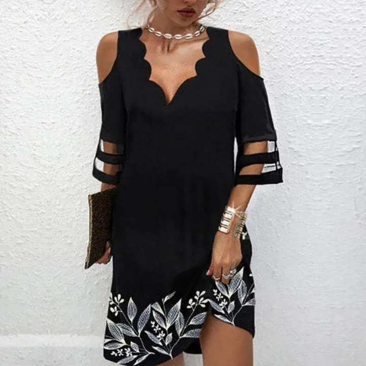 Zwarte off-shoulder jurk met bloemenprint en opengewerkte mouwen, gedragen door een vrouw. Perfect voor zomerfeestjes en casual chique gelegenheden.
