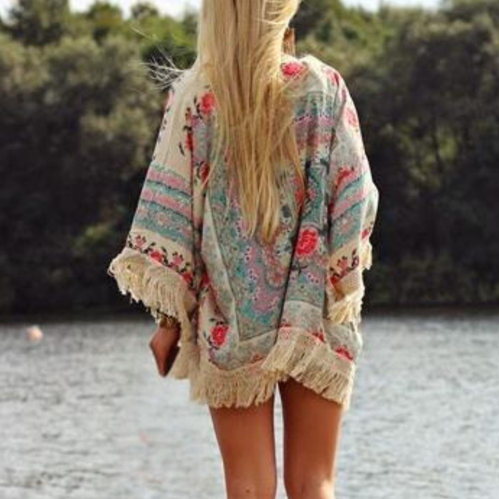 Vrouw in kleurrijke kimono met bloemenprint en franjes, staand bij een meer. Zomermode, boho-stijl, outdoor, natuur.