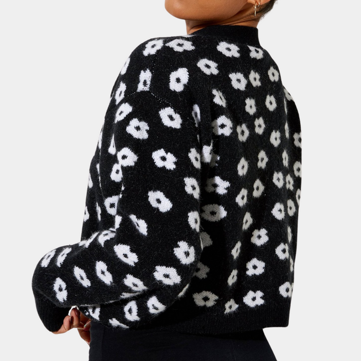 Zwarte gebreide trui met witte bloemenprint, lange mouwen en ronde hals. Modieuze dameskleding, ideaal voor herfst- en winterseizoenen.