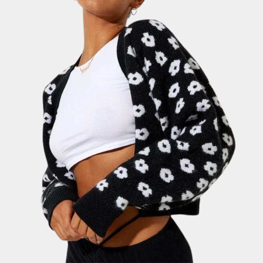 Zwarte gebreide bolero met witte bloemenprint, gedragen over een wit T-shirt. Trendy damesmode, stijlvolle herfstkleding, casual outfit.