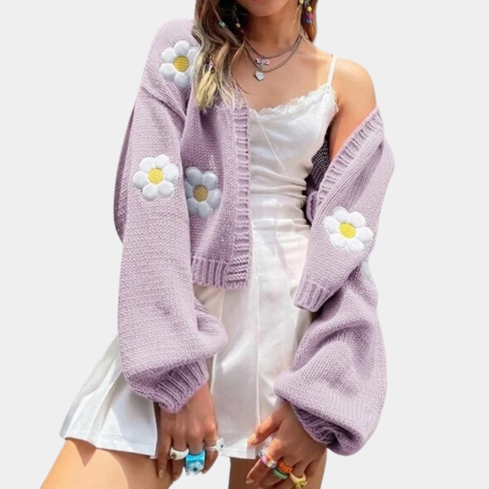 Vrouw in witte jurk met lila gebreid vest met madeliefjes, trendy mode, kleurrijke ringen, casual lente-zomer outfit.