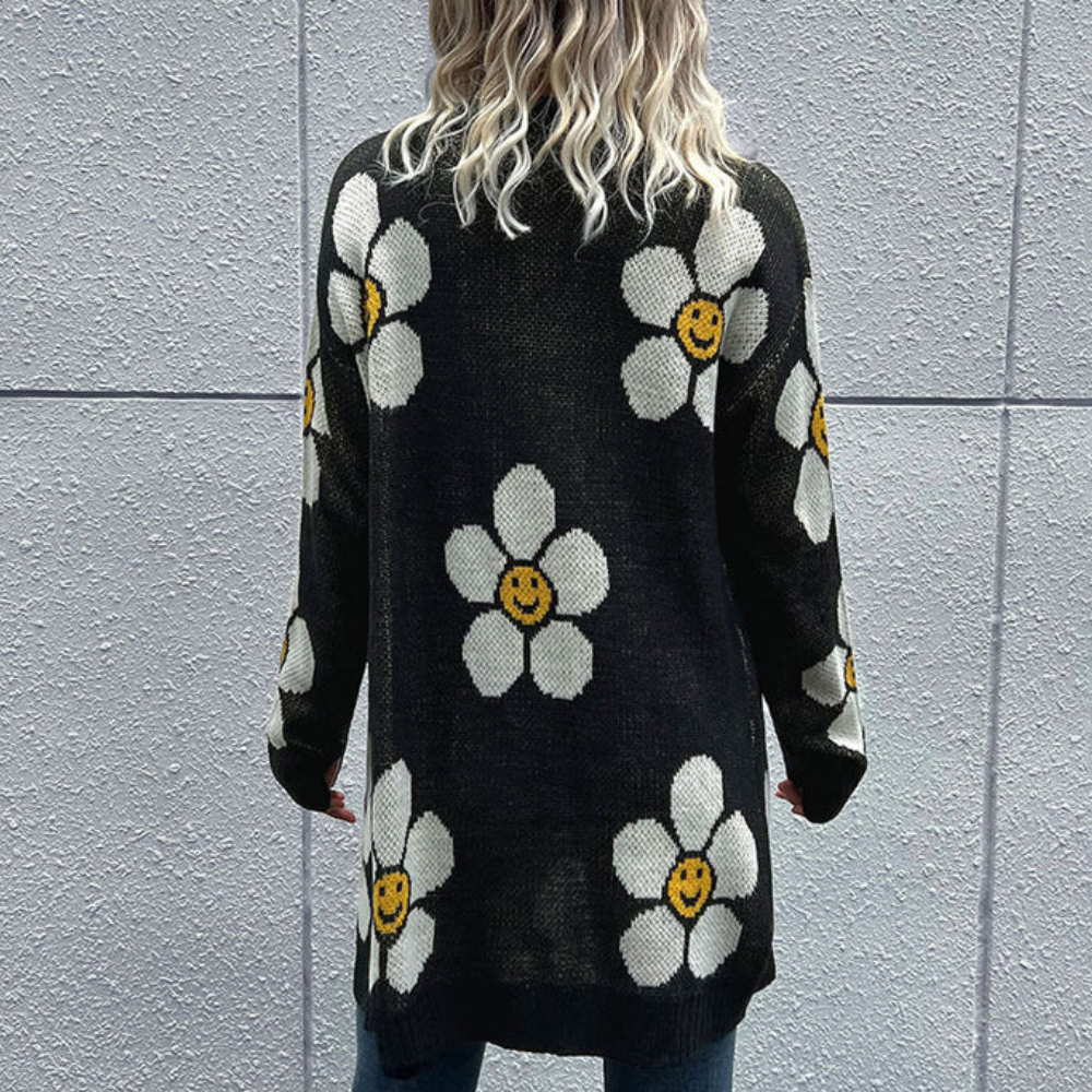 Zwarte trui met lange mouwen, versierd met witte bloemen en gele smiley gezichten. Perfect voor casual mode en herfstkleding.
