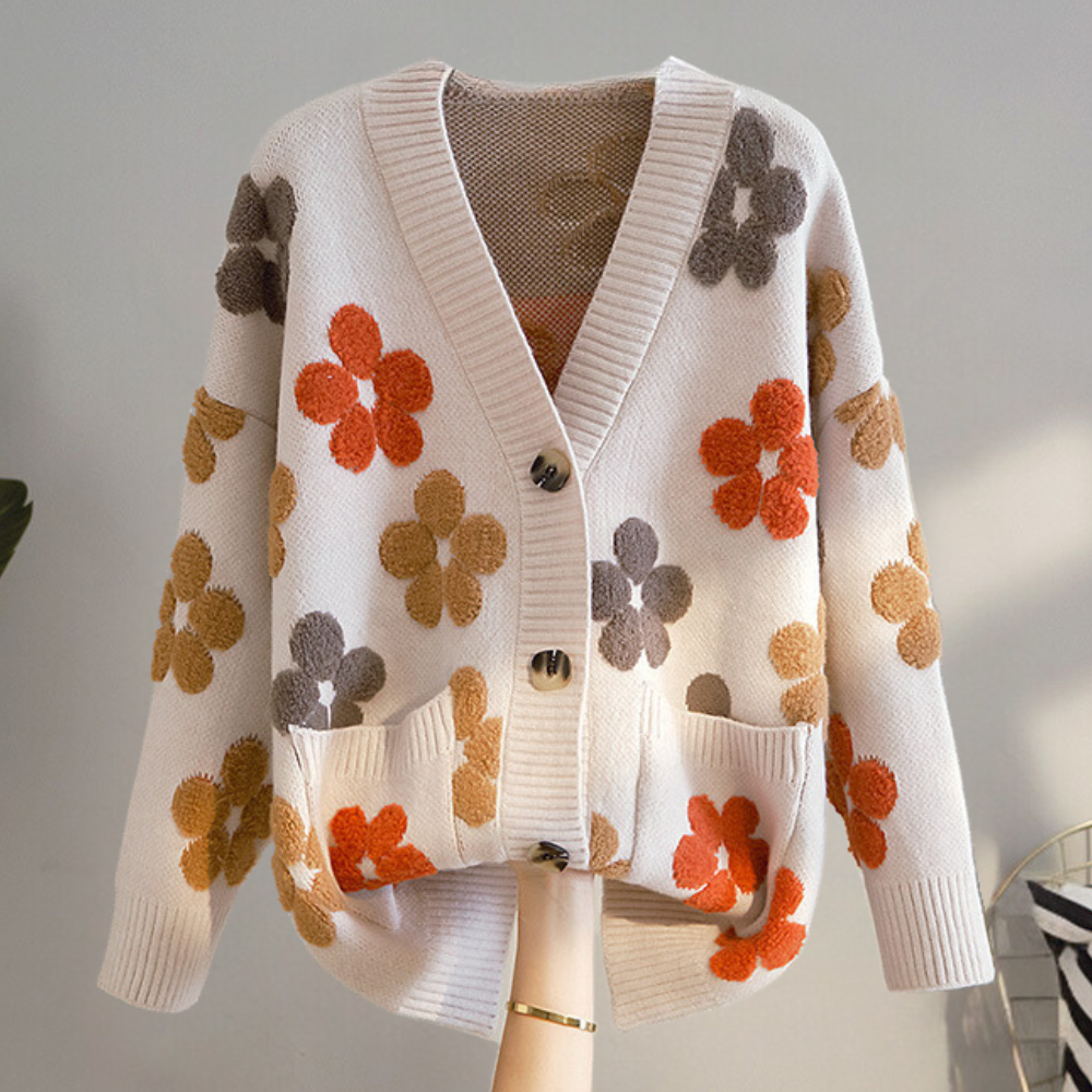 Crèmekleurig damesvest met bloemenpatroon, V-hals en knopen. Trendy gebreid ontwerp, ideaal voor herfstmode. Comfortabel en stijlvol.