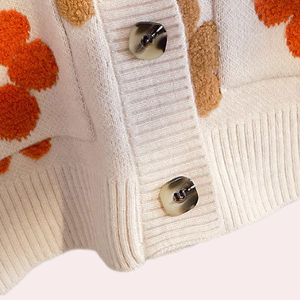 Crèmekleurig gebreid vest met bloemenpatroon, metalen knopen en ribbels. Trendy damesmode, herfstkleding, comfortabele stijl.