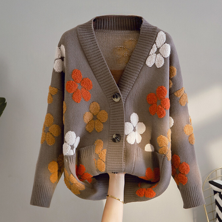 Grijze damestrui met bloemenpatroon, V-hals en knopen. Trendy herfstmode, gebreid vest met oranje en witte bloemen. Comfortabele casual stijl.