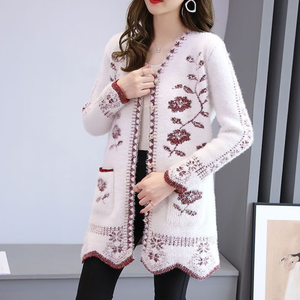 Vrouw draagt witte gebreide cardigan met rode bloemenprint, lange mouwen en zakken. Modieuze dameskleding, herfst-winter stijl.