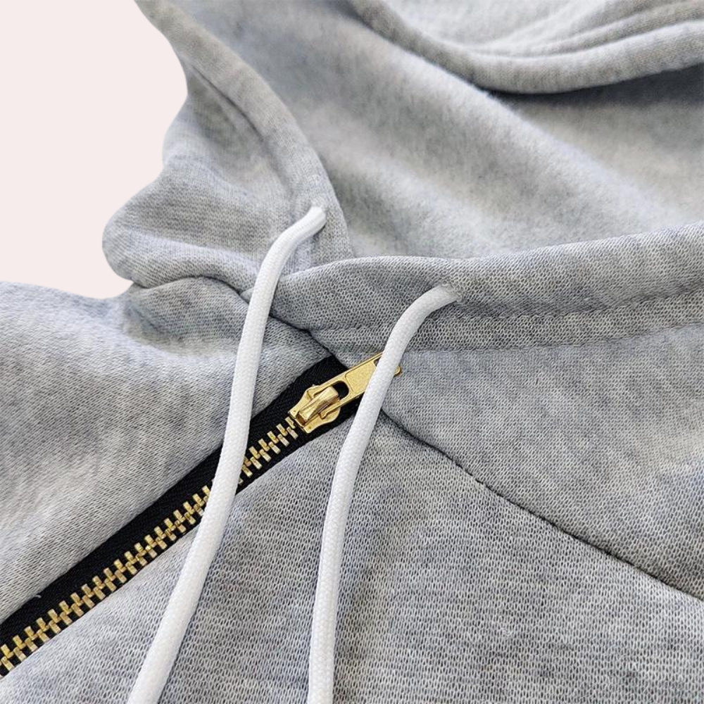Grijze hoodie met ritssluiting en witte trekkoorden, close-up. Comfortabele katoenen stof, casual mode, streetwear stijl.