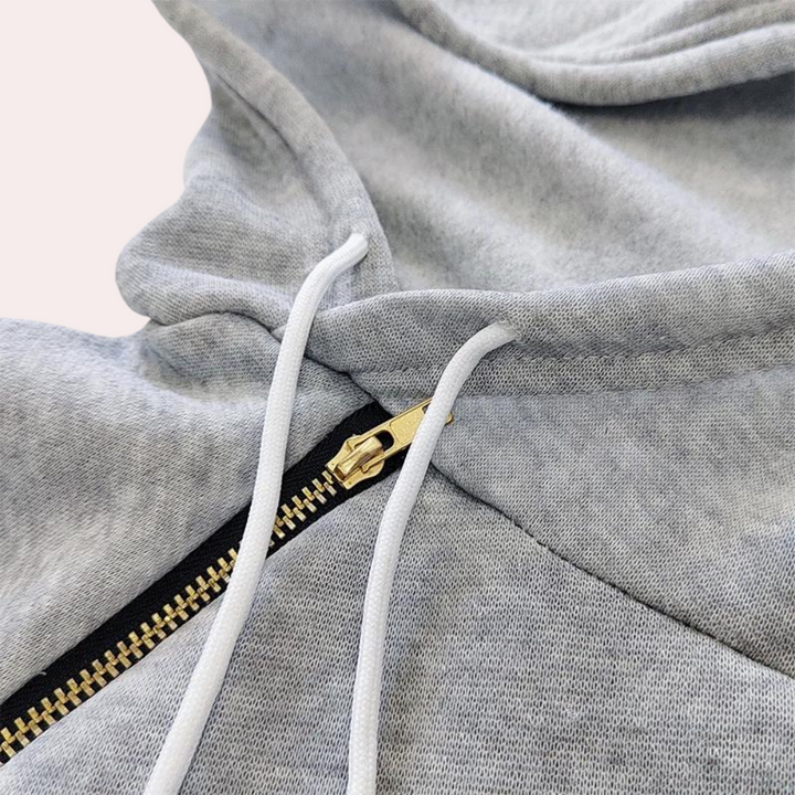 Grijze hoodie met ritssluiting en witte trekkoorden, close-up. Comfortabele katoenen stof, casual mode, streetwear stijl.