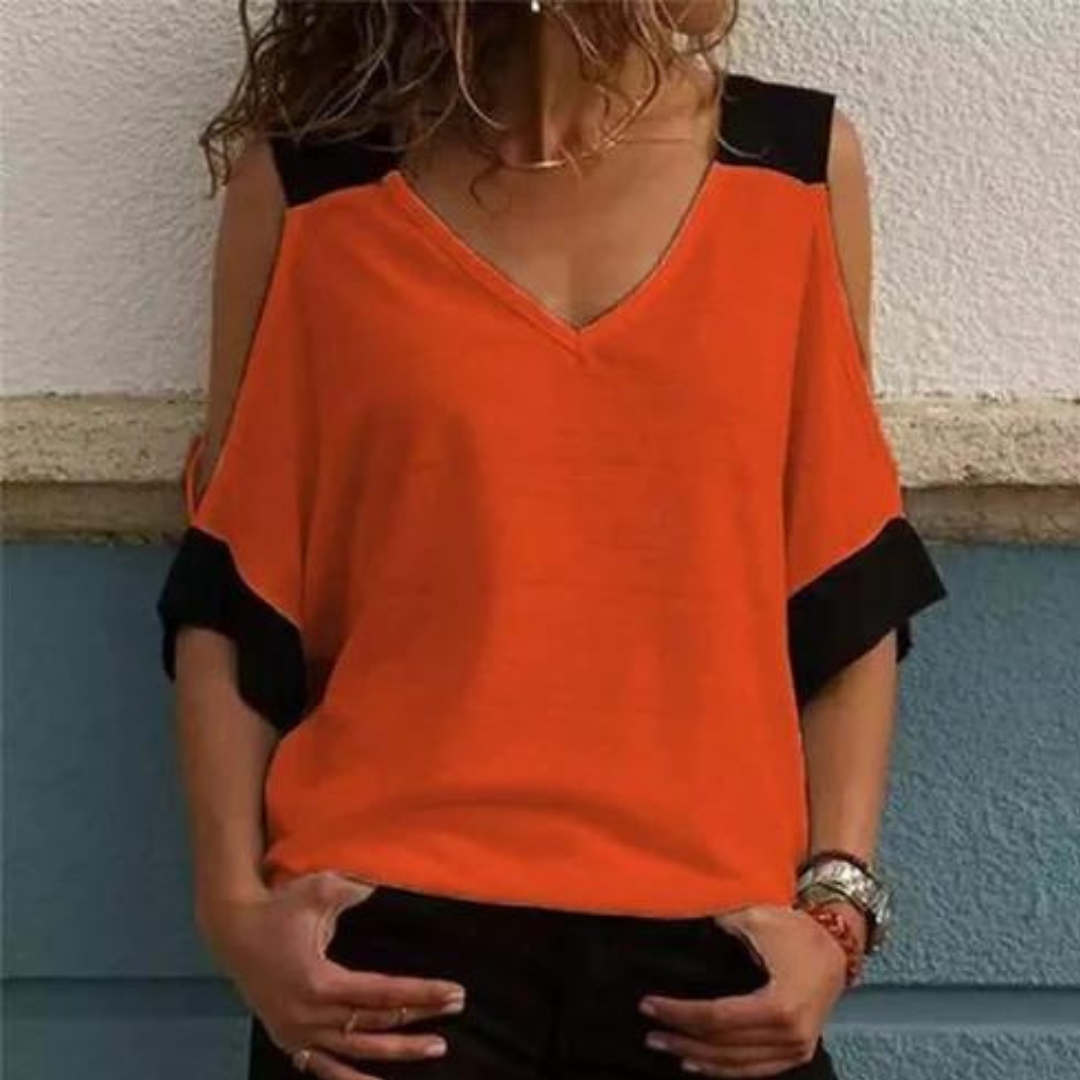 Vrouw draagt oranje blouse met zwarte accenten, V-hals en open schouders. Modieuze dameskleding, trendy zomeroutfit, casual stijl.
