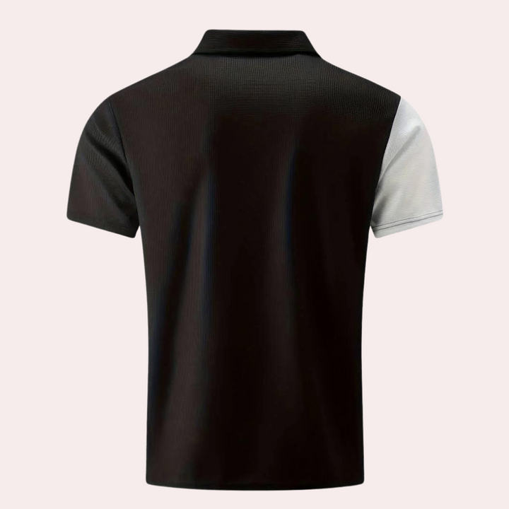 Zwarte polo met korte mouwen, contrasterende witte rechtermouw, gemaakt van ademende stof. Ideaal voor casual en sportieve gelegenheden.