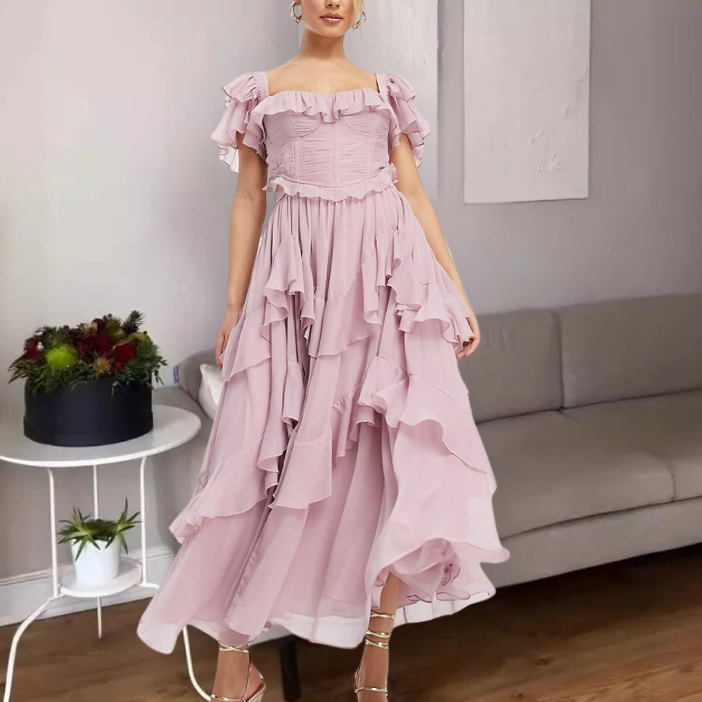 Vrouw in roze off-shoulder jurk met ruches, staand in moderne woonkamer. Elegante avondjurk, trendy mode, stijlvolle kleding.