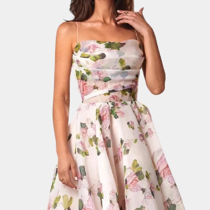Vrouw in elegante witte bloemenjurk met roze en groene accenten, mouwloos ontwerp, geschikt voor zomerfeesten en bruiloften.