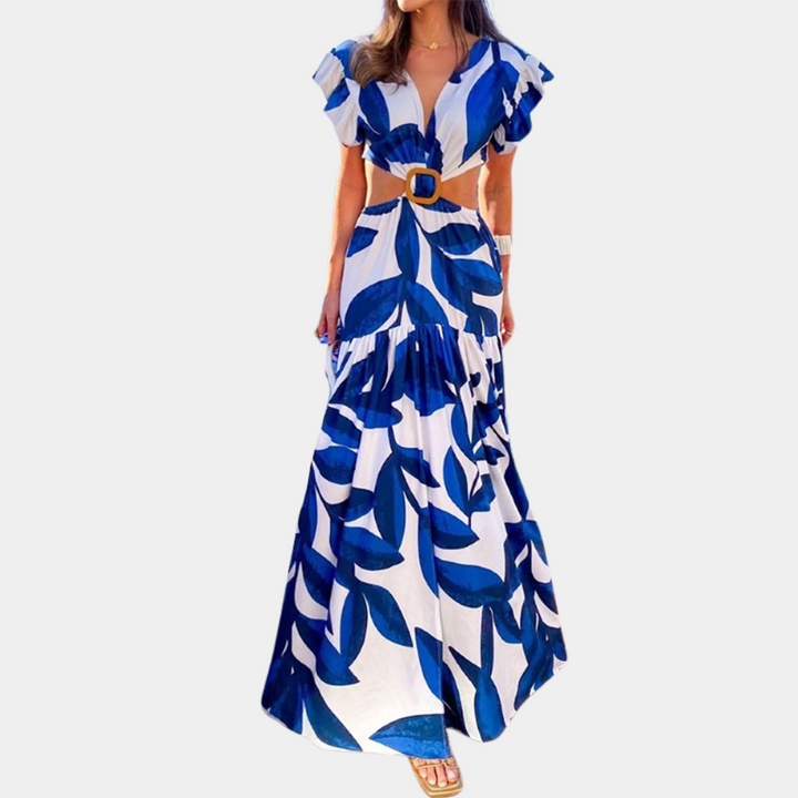 Vrouw in lange, witte zomerjurk met blauwe bladerenprint en uitgesneden details, perfect voor strandmode. Trendy dameskleding, boho-stijl.