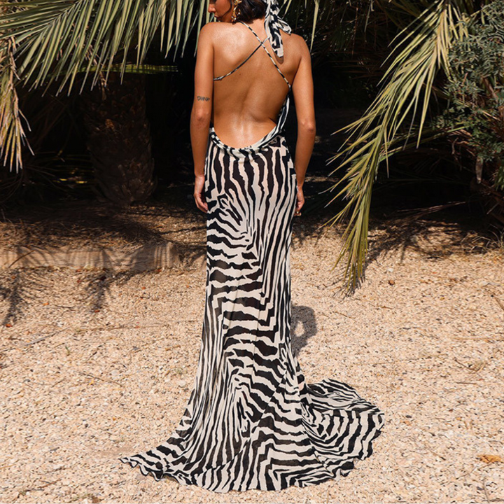 Zwart-witte zebraprint jurk met open rug, gedragen door vrouw in zomerse omgeving. Perfect voor strandmode en trendy zomeroutfits.