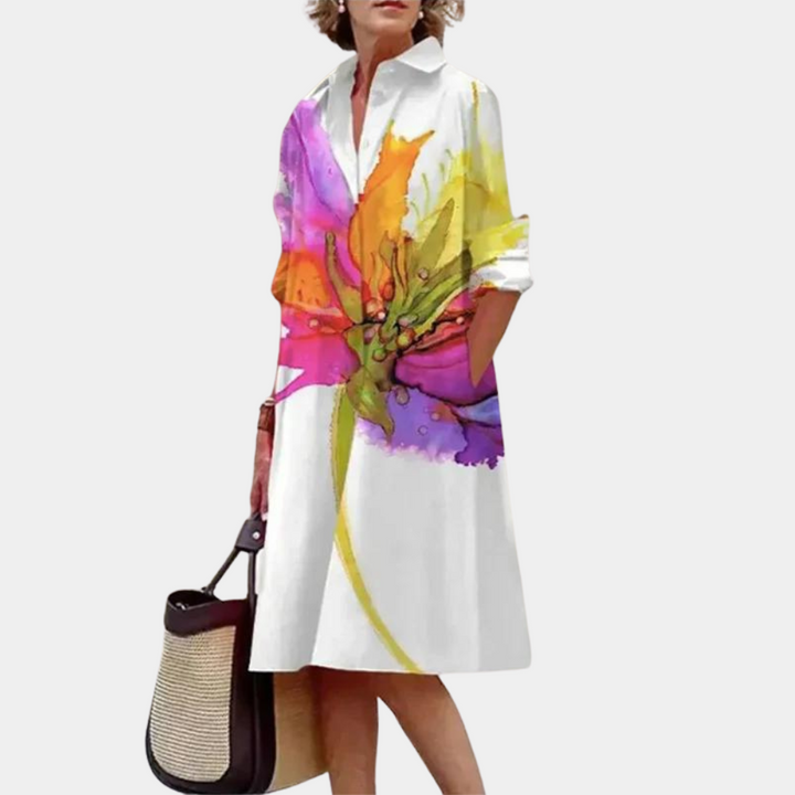 Vrouw in witte jurk met kleurrijke bloemenprint, draagt een zwarte en beige tas. Stijlvolle damesmode, casual zomerjurk, trendy outfit.