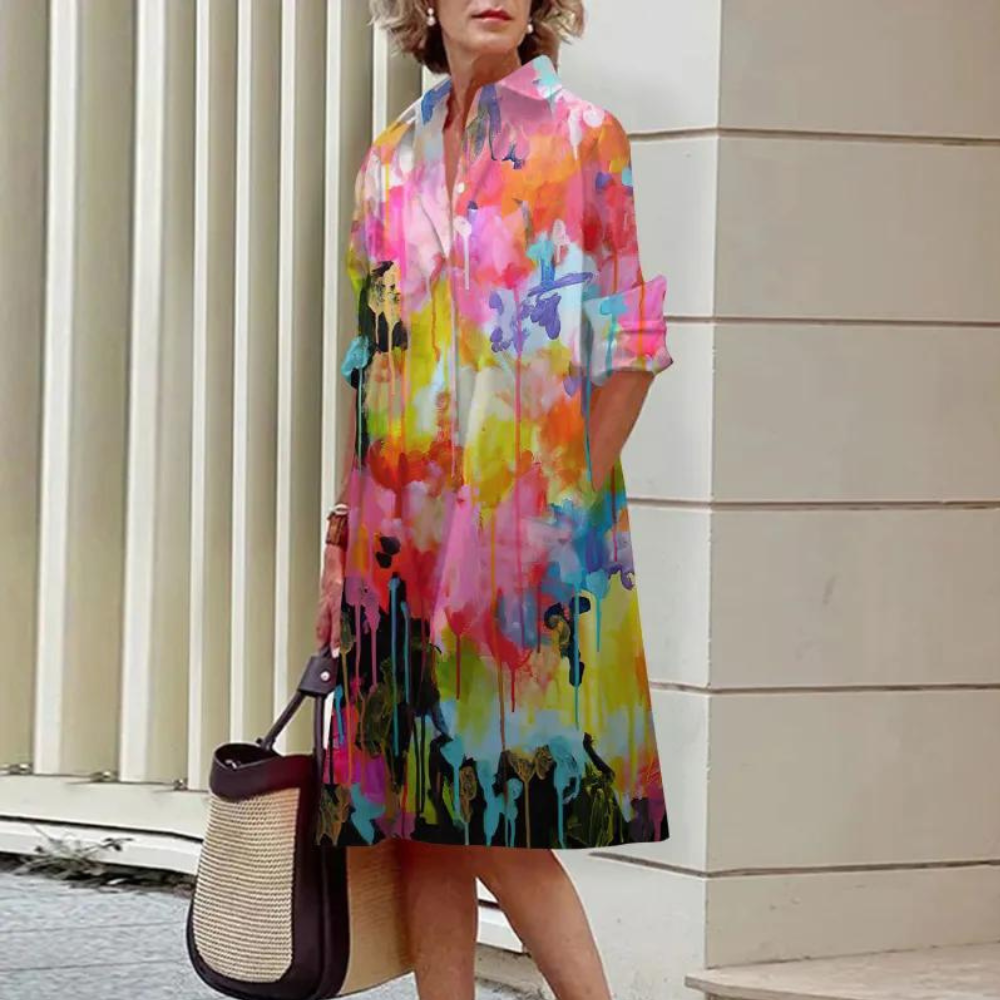 Vrouw in kleurrijke abstracte jurk met bloemenprint, draagt een rieten tas. Stijlvolle mode, zomerkleding, casual chique outfit.
