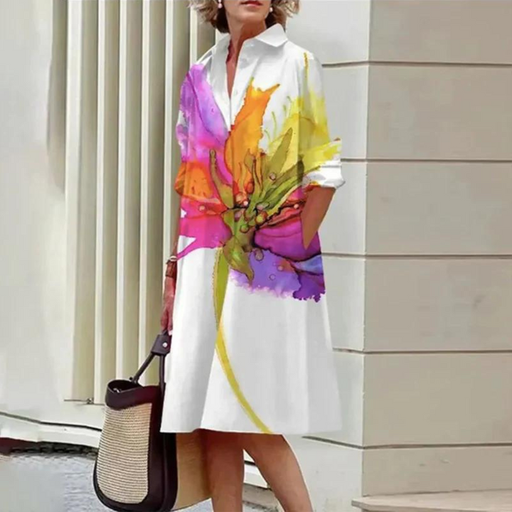 Vrouw in witte jurk met kleurrijke bloemenprint, draagt een handtas. Stijlvolle mode, casual zomeroutfit, trendy dameskleding.