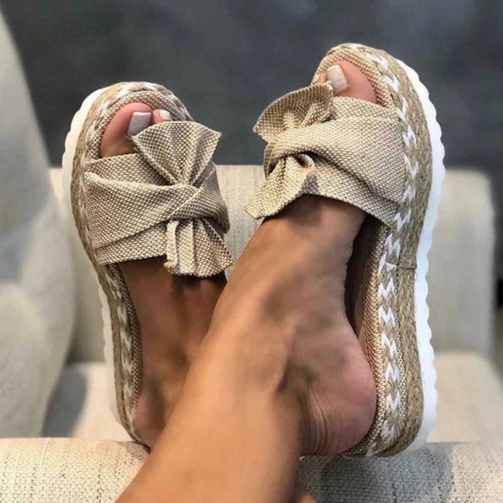 Beige sandalen met strik, gevlochten zool en witte stiksels, perfect voor zomerse outfits. Comfortabele damesmode, trendy en stijlvol.