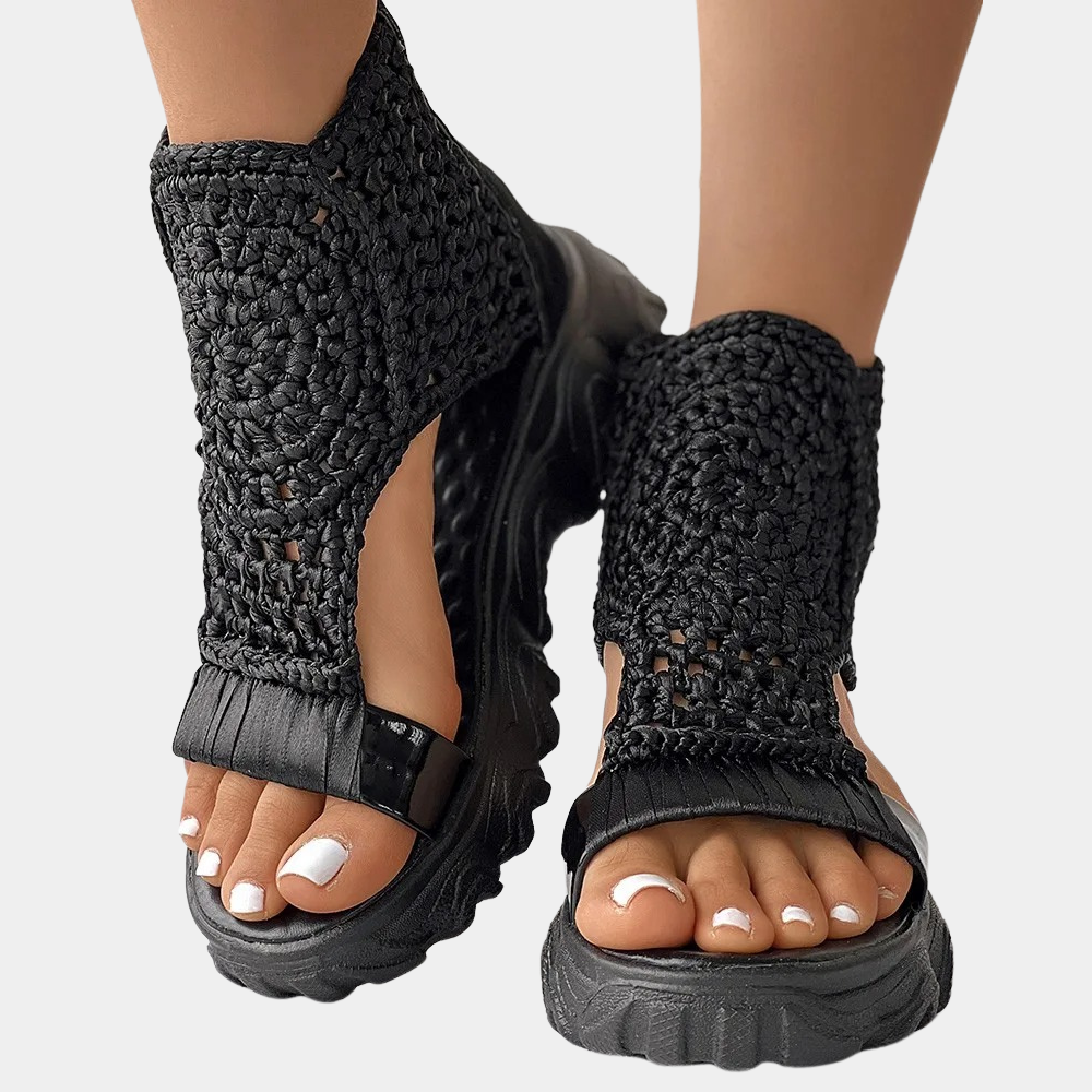 Zwarte gevlochten sandalen met dikke zool, gedragen door een persoon. Trendy zomerschoeisel, comfortabel en stijlvol voor dagelijks gebruik.