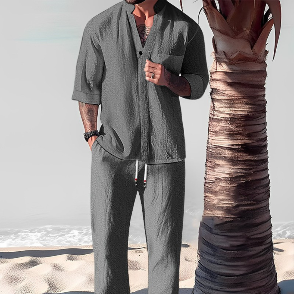 Grijze herenlinnen set met overhemd en broek, strandachtergrond, casual zomeroutfit, comfortabele kleding, modieuze herenkleding.
