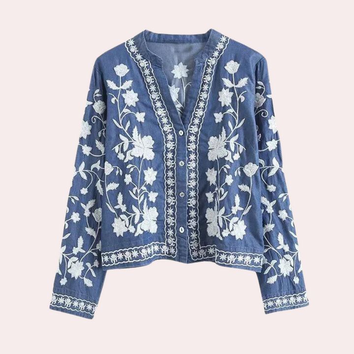 Donkerblauwe damesblouse met witte bloemenborduursels, lange mouwen en knoopsluiting. Boho-stijl, perfect voor casual en chique outfits.