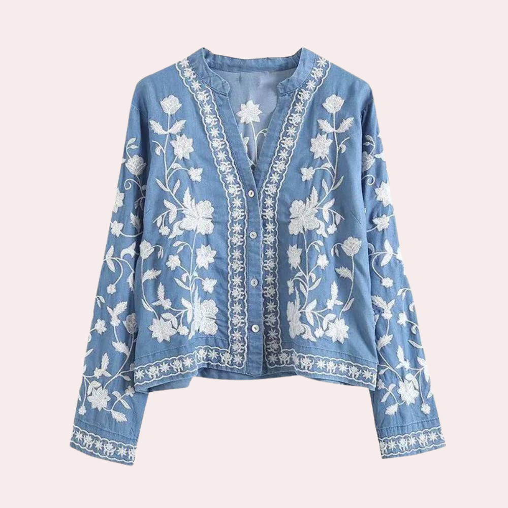 Blauwe damesblouse met witte bloemenborduursels, lange mouwen en knoopsluiting. Perfect voor casual en bohemian stijlen.