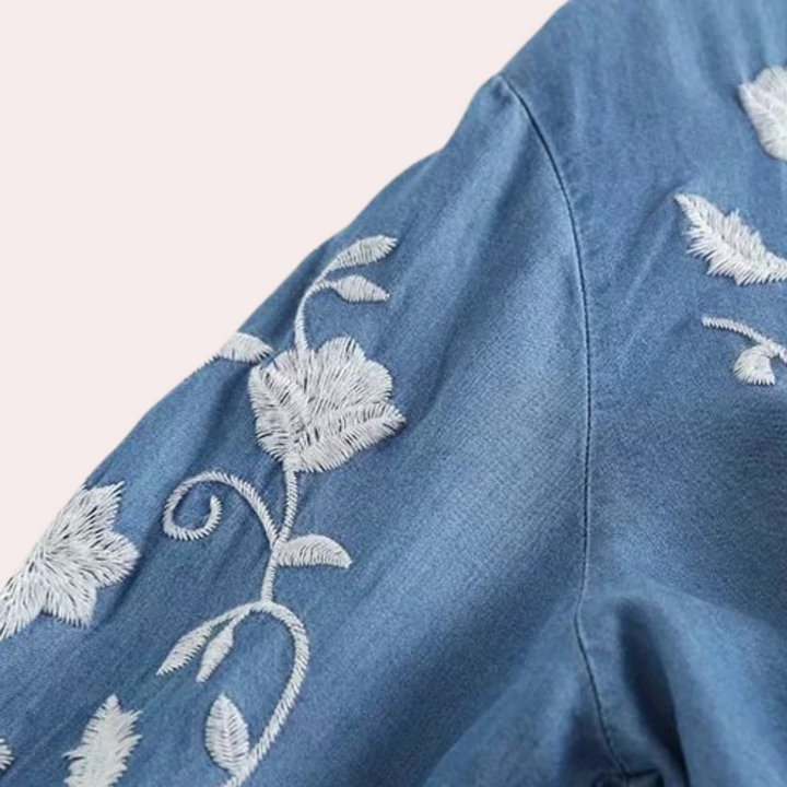 Blauwe denim blouse met witte bloemenborduursels op de mouw, modieuze dameskleding, casual stijl, hoogwaardige stof, trendy design.
