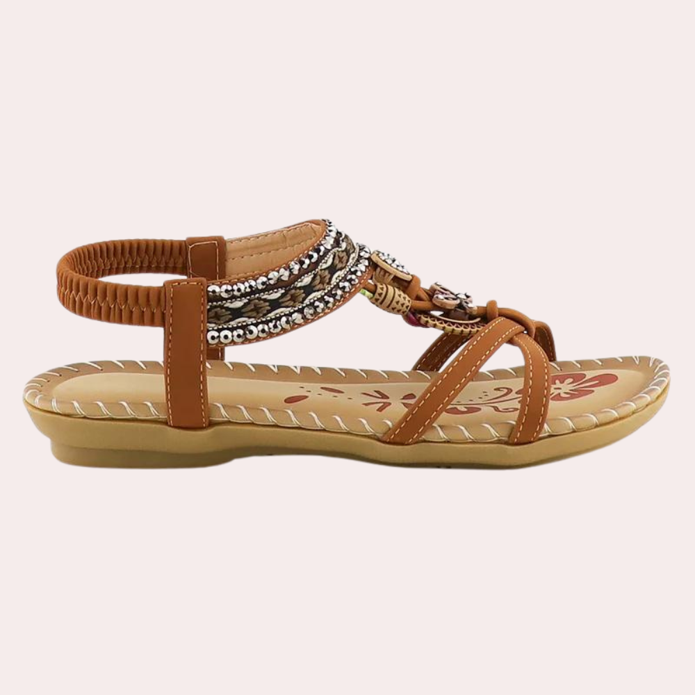 Bruine damessandaal met kralen en gevlochten bandjes, platte zool en elastische hielband. Perfect voor zomerse outfits en casual gelegenheden.