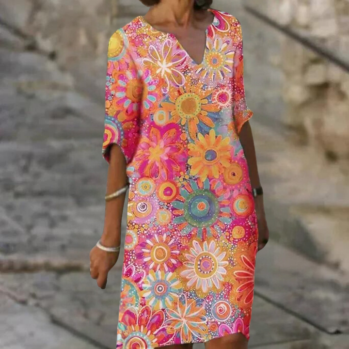 Vrouw in kleurrijke bloemenjurk met korte mouwen, levendig patroon van zonnebloemen en madeliefjes, zomermode, casual stijl.