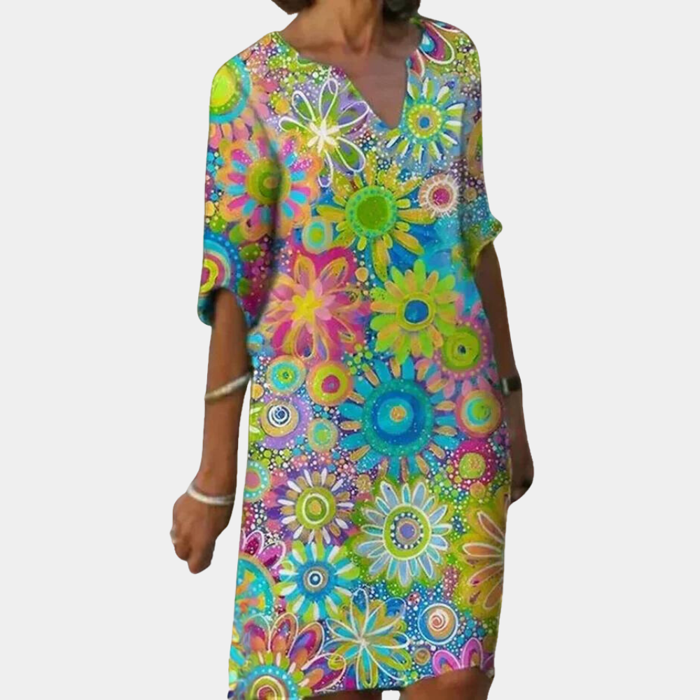 Vrouw in kleurrijke zomerjurk met bloemenprint, korte mouwen en V-hals. Perfect voor casual en strandkleding. Bloemenjurk, damesmode, zomerstijl.