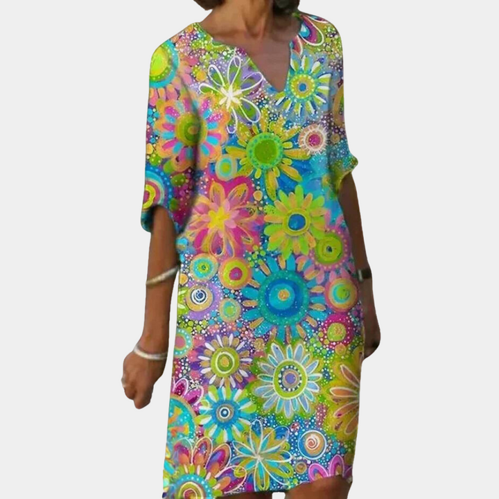 Vrouw in kleurrijke zomerjurk met bloemenprint, korte mouwen en V-hals. Perfect voor casual en strandkleding. Bloemenjurk, damesmode, zomerstijl.