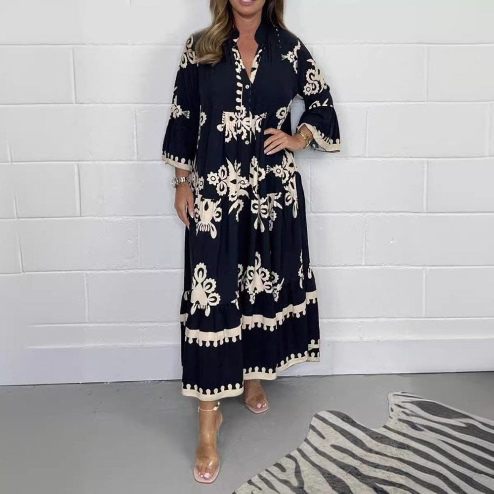 Zwarte maxi-jurk met witte bloemenprint, driekwart mouwen en V-hals. Perfect voor zomeravonden en casual chique gelegenheden.