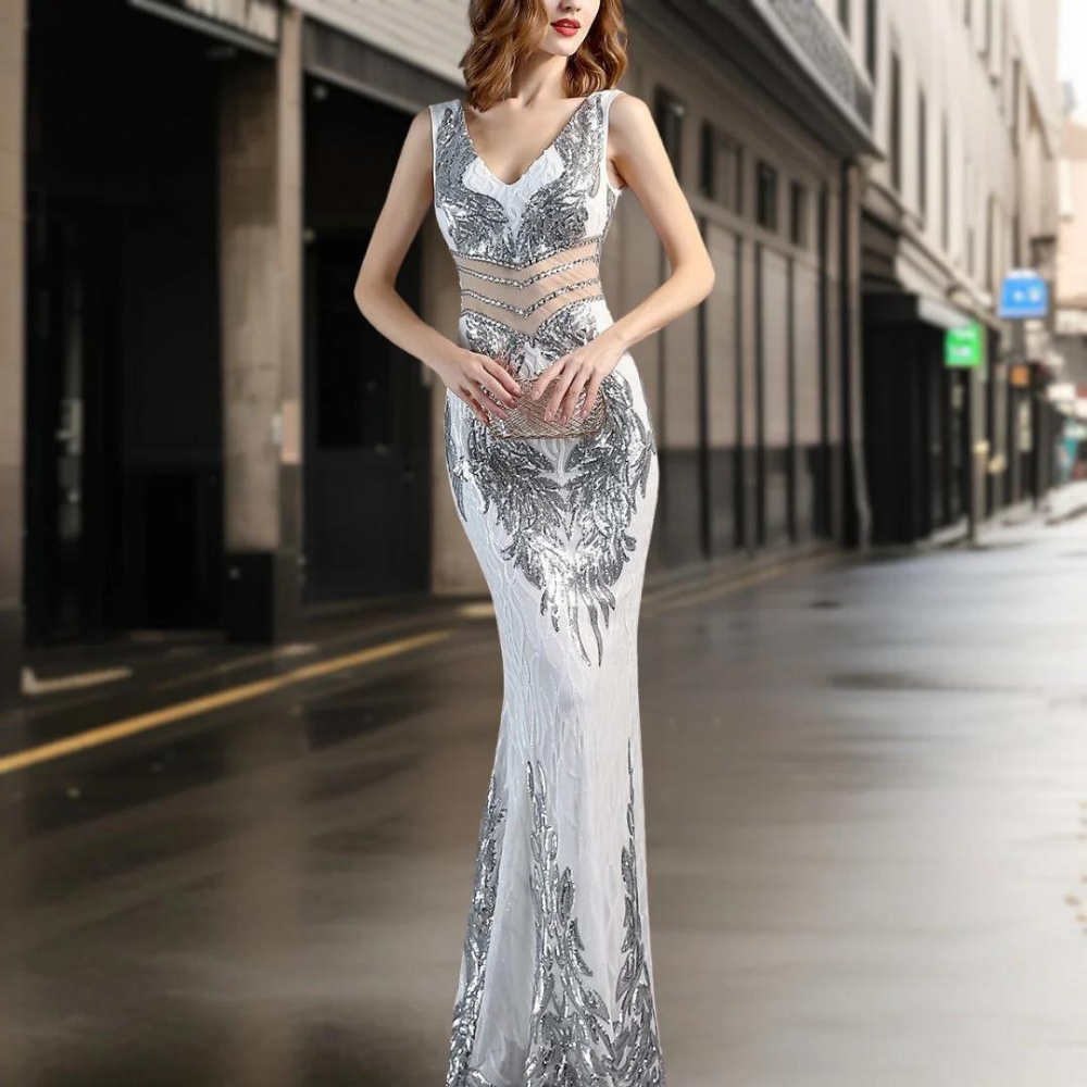 Elegante zilveren avondjurk met glinsterende pailletten en transparante details, perfect voor galafeesten en speciale gelegenheden.