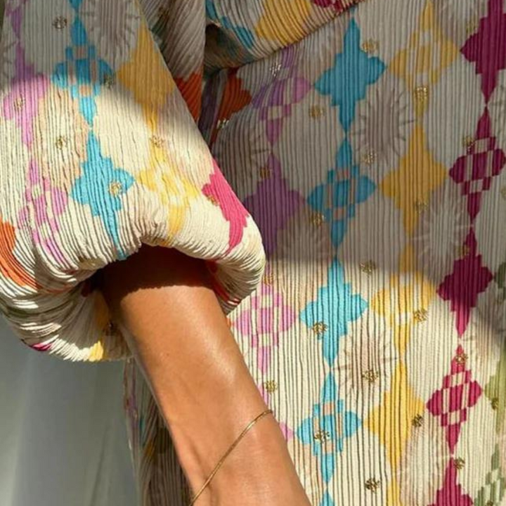 Kleurrijke geplooide jurk met geometrisch patroon in roze, blauw en geel. Zomermode, dameskleding, trendy design, stijlvolle outfit.