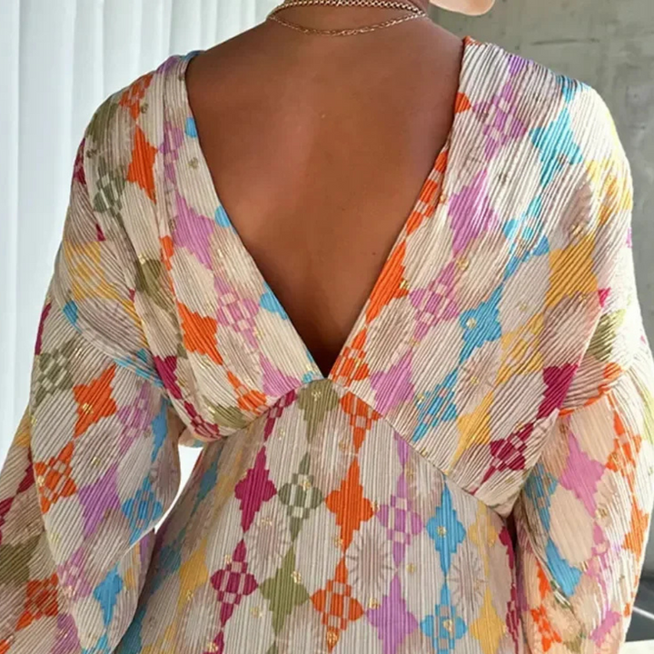 Vrouw in kleurrijke, geometrisch patroon jurk met diepe V-hals, rugaanzicht. Trendy damesmode, opvallende kleuren, stijlvolle kleding.