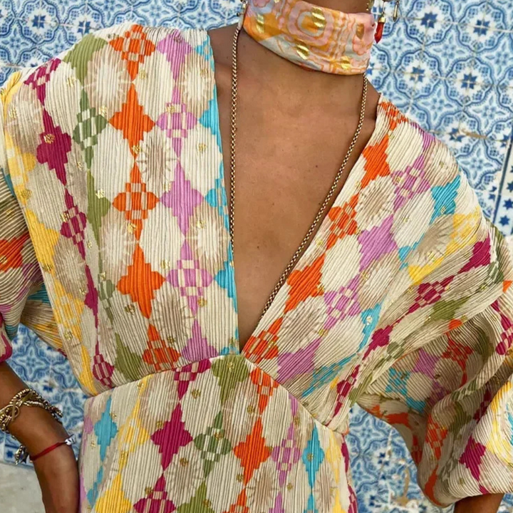 Kleurrijke boho jurk met ruitpatroon, diepe V-hals en wijde mouwen, gedragen door model. Perfect voor zomerse bohemian stijl.